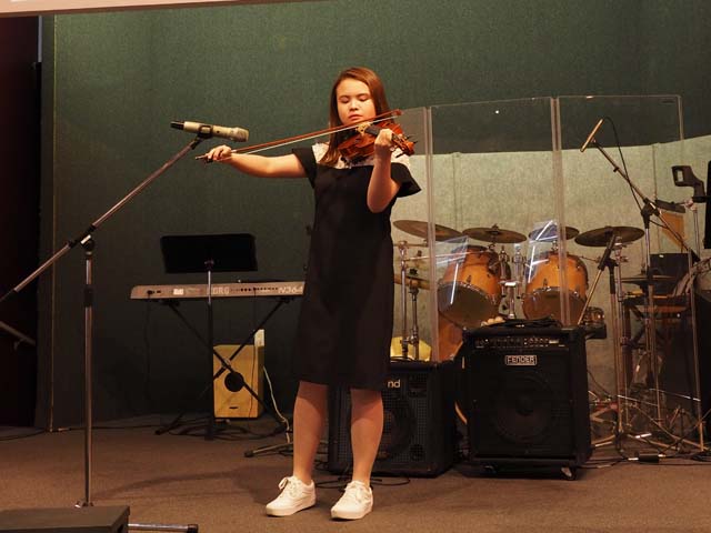 girl playing violin at school talent show