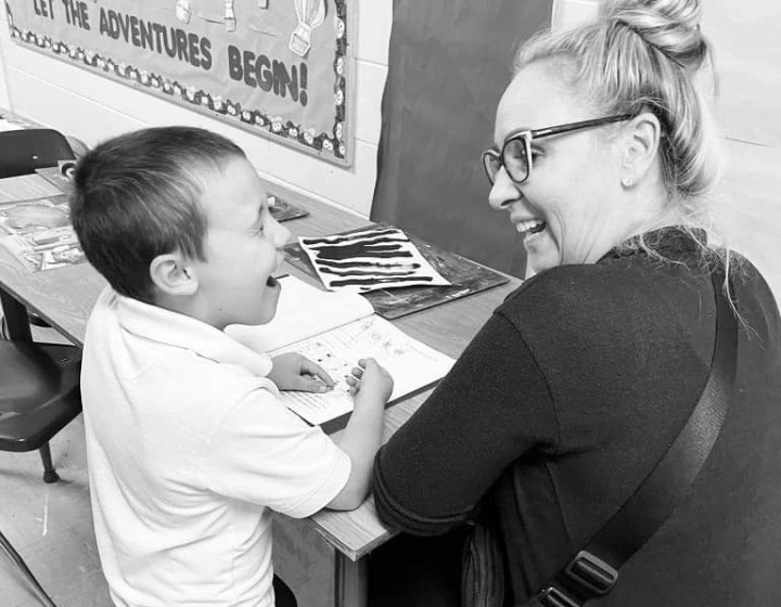 black and white image of elementary student and teaching smiling at one another