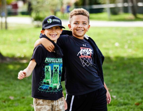 Portrait of two elementary aged students in a friendly embrace.