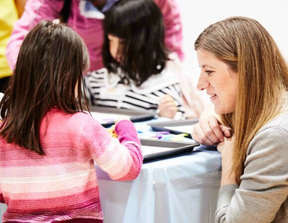 Teacher observing an elementary student's work and smiling