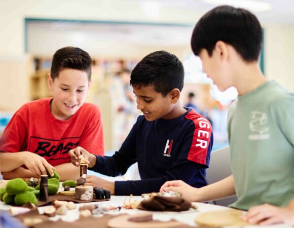 Three elementary aged students constructing an outdoor scene.